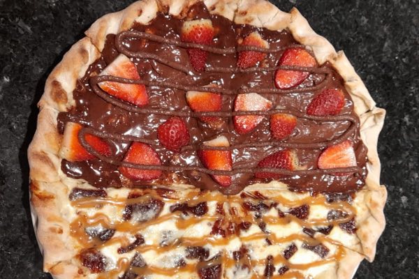 Sweet pizza topped with chocolate, strawberries and banana.