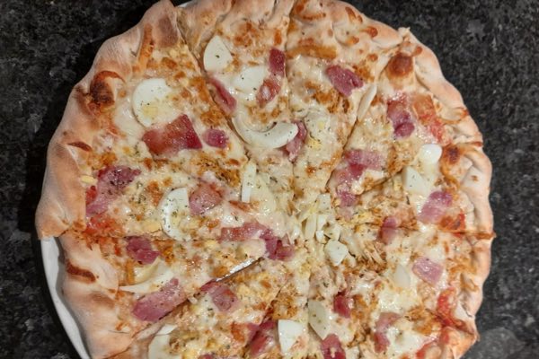 Pizza with ham and melted cheese, edge to edge on a stuffed crust.